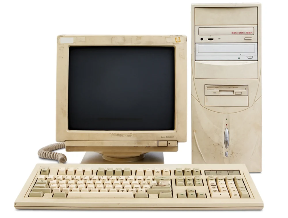 A stock photo of a tower computer connected to a CRT monitor and a keyboard. All of them are dirty white and look old.